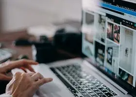 A person working on a laptop browsing visual content in an indoor setting, capturing digital creativity and remote work.