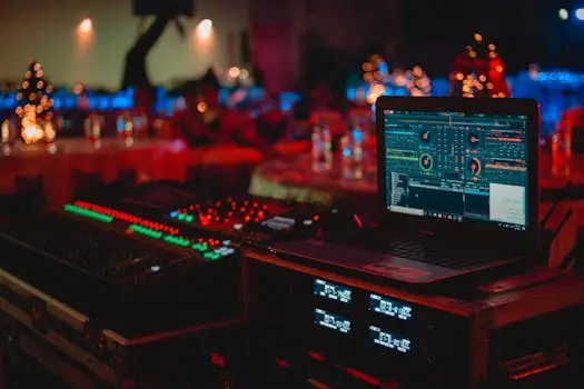 Vivid DJ setup with laptop and sound mixer at a lively indoor event.